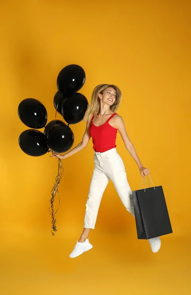 Happy Young Woman Balloons Shopping Bag Jumping Yellow Background Black — Stock Photo, Image