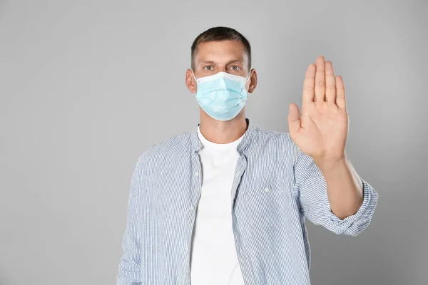 Man Skyddsmask Visar Stop Gest Grå Bakgrund Förhindra Spridning Coronavirus — Stockfoto