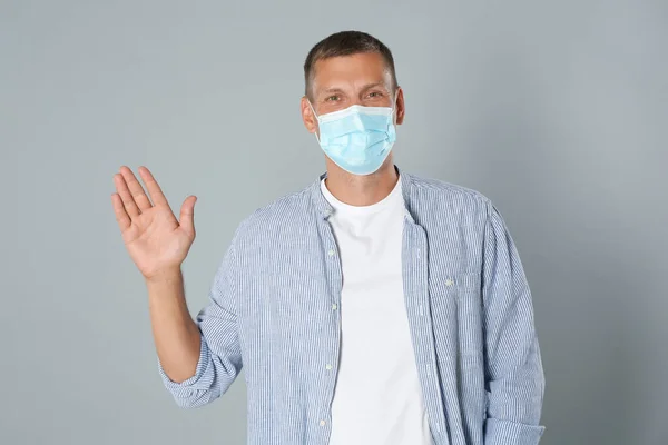 Man Protective Mask Showing Hello Gesture Grey Background Keeping Social — Stock Photo, Image