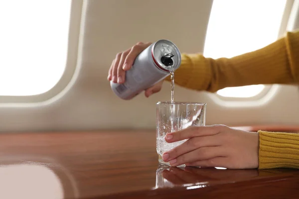 Woman pouring water on plane, closeup. Comfortable flight