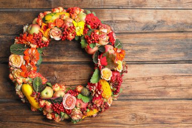 Ahşap arka planda çiçekli, meyveli ve meyveli güzel bir sonbahar çelengi. Metin için boşluk