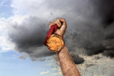 Kazanan, altın madalyayla gökyüzüne doğru elini kaldırıyor.