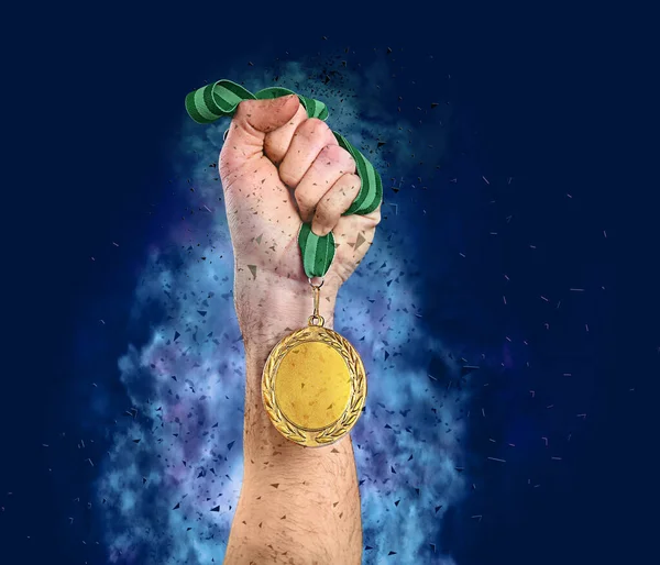 Winner raising hand with gold medal surrounded by fume and shatters on blue background, closeup