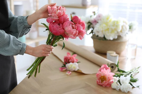 花の配達人がテーブルで牡丹の花束を作って — ストック写真