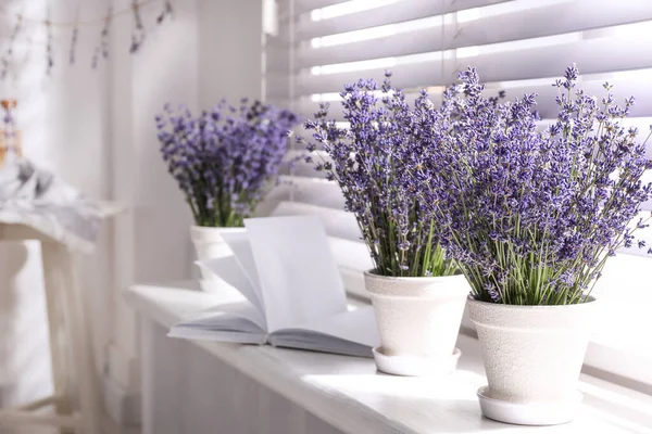 Beautiful lavender flowers and book on window sill indoors. Space for text