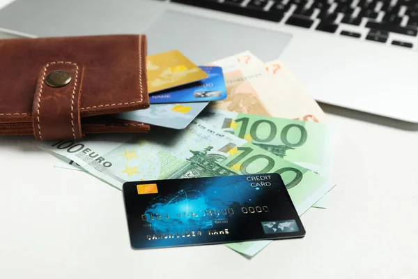 Credit cards, banknotes and wallet on white table