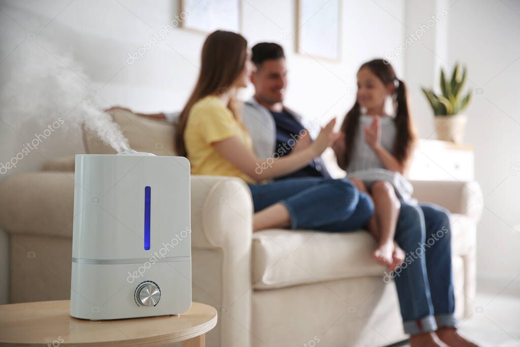 Modern air humidifier and blurred family on background