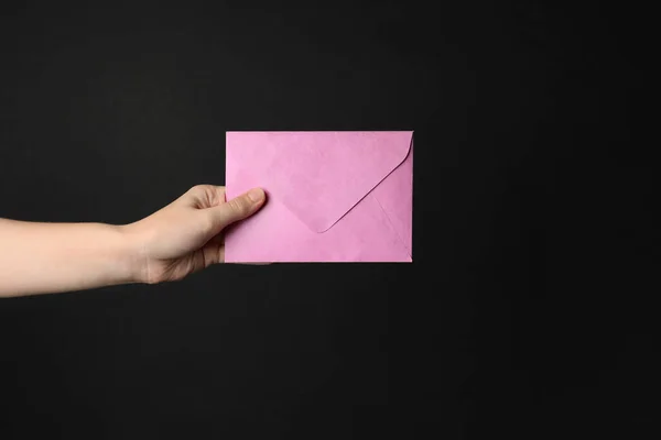 Mulher Segurando Envelope Papel Rosa Fundo Preto Close — Fotografia de Stock