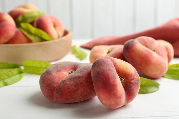 Fresh ripe donut peaches on white wooden table, closeup