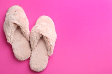 Pembe arka planda bir çift şık yumuşak terlik. Metin için boşluk