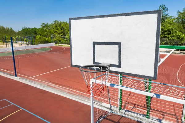 Basketball backboard over football gat at outdoor sports complex on sunny day