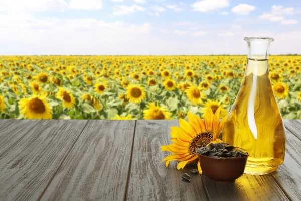 Sonnenblumenöl Und Samen Auf Einem Holztisch Der Nähe Eines Blühenden — Stockfoto