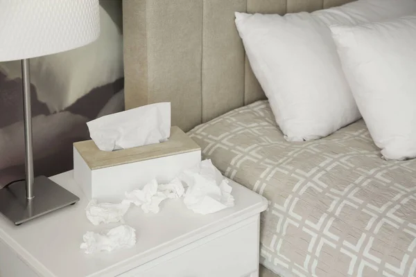 Used paper tissues and holder on table in bedroom
