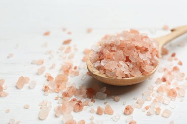 Kaşık ve pembe himalaya tuzu beyaz ahşap masada, yakın plan.