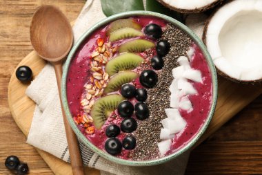 Lezzetli acai smoothie ve ahşap masada servis edilen meyveler.