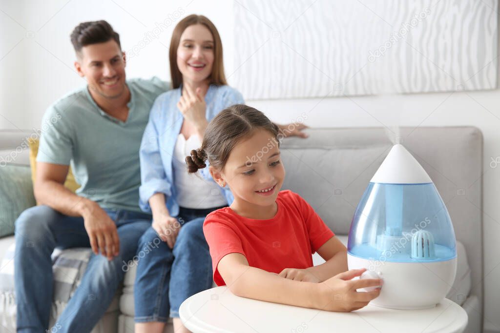 Little girl using modern air humidifier near her parents at home