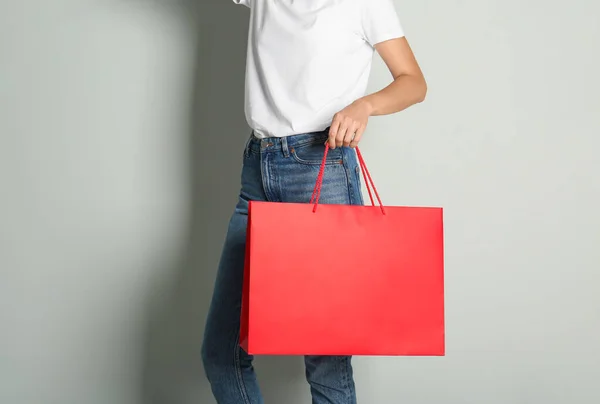 薄いグレーの背景に紙の買い物袋を持つ女性 クローズアップ — ストック写真