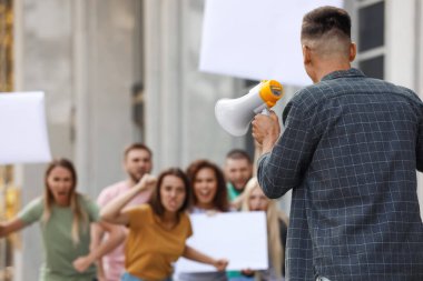 Protesto lideri megafonla dışarıda kalabalıkla konuşuyor.