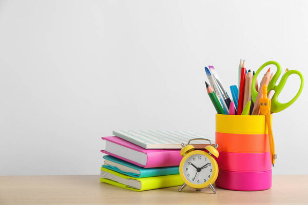Different school stationery and alarm clock on table against white background, space for text. Back to school