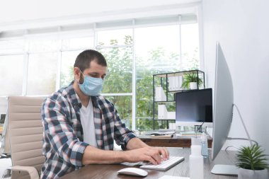 İş yerinde solunum maskesi takan bir ofis çalışanı