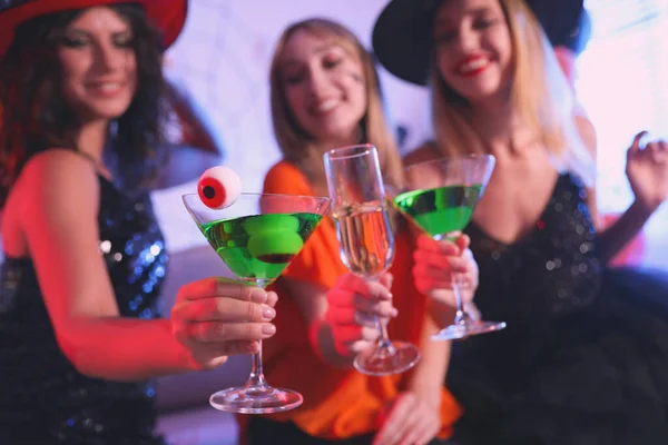 Group of friends toasting with cocktails at Halloween party indoors