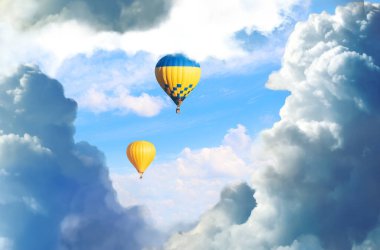 Harika rüyalar. Mavi gökyüzünde kabarık bulutlu sıcak hava balonları 