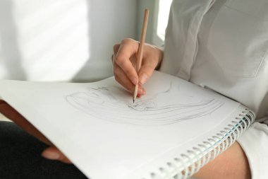 Not defterine kurşun kalemle kızın portresini çizen kadın, yakın plan.