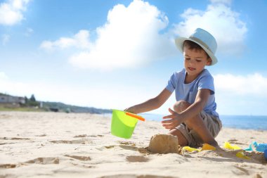 Kumsalda plastik oyuncaklarla oynayan sevimli bir çocuk.