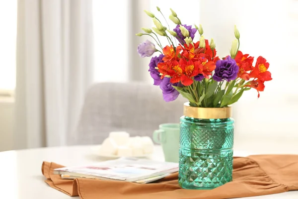 Glass vase with fresh flowers and magazines on table indoors. Space for text