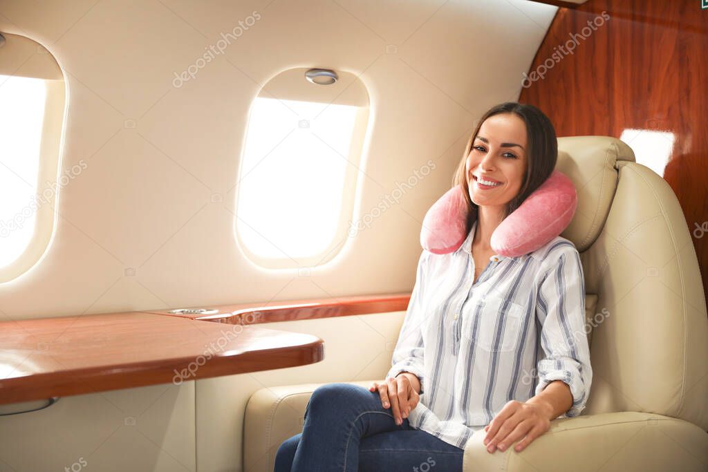 Happy woman with neck pillow on plane