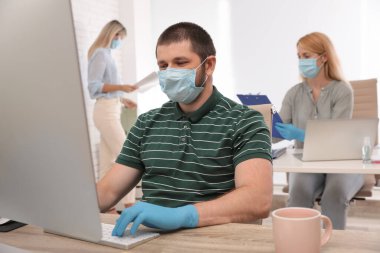 Ofis çalışanları iş yerinde solunum maskesi takıyor.
