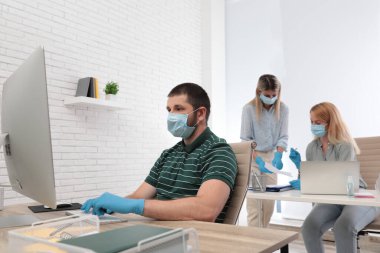İş yerinde maske ve eldiven takan ofis çalışanları