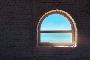 Güzel gökyüzü ve deniz tuğla duvardaki eski pencereden görülebilir. 