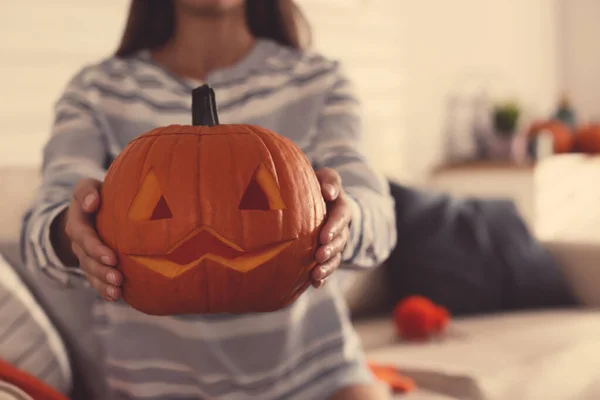 Woman holding pumpkin jack o\'lantern indoors, closeup with space for text. Halloween celebration