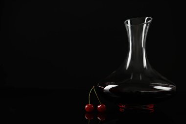 Lezzetli kiraz şarabı ve siyah arka planda olgun meyveler. Metin için boşluk