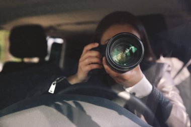 Kameralı özel dedektif arabadan gözetliyor.