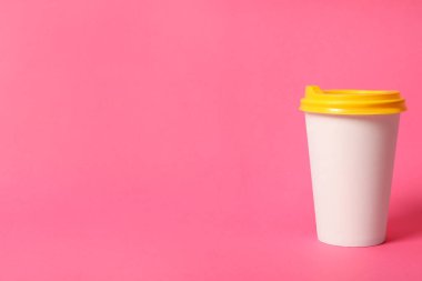 Pembe arka planda paket kağıttan kahve fincanı. Metin için boşluk