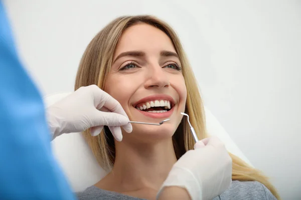 医者は軽い背景で患者の歯を調べる 化粧品歯科 — ストック写真