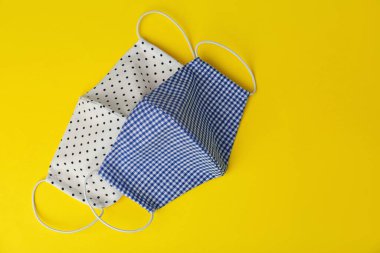 Sarı arka planda ev yapımı koruyucu maskeler, düz yatış. Metin için boşluk