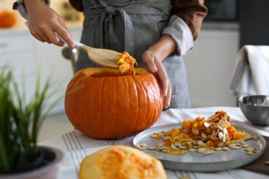 İçerideki masada balkabağı Jack O 'Lantern yapan kadın. Cadılar Bayramı