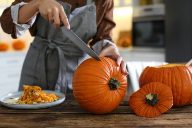 Mutfaktaki masada balkabağı oyan bir kadın. Cadılar Bayramı
