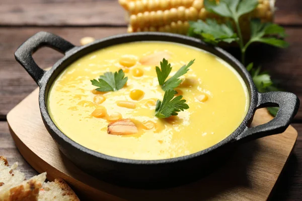 Delicious creamy corn soup on wooden table, closeup