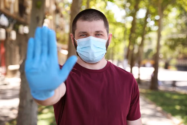 얼굴을 보호하는 마스크를 남자가 바깥에서 몸짓을 멈춘다 코로나 바이러스의 확산을 — 스톡 사진