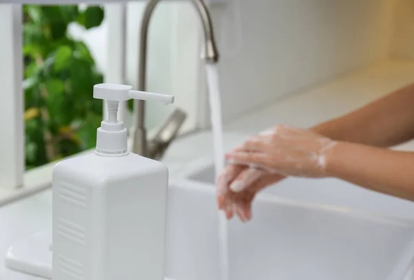 Bir Şişe Antibakteriyel Sabun Arka Planda Ellerini Yıkayan Bir Kadın — Stok fotoğraf