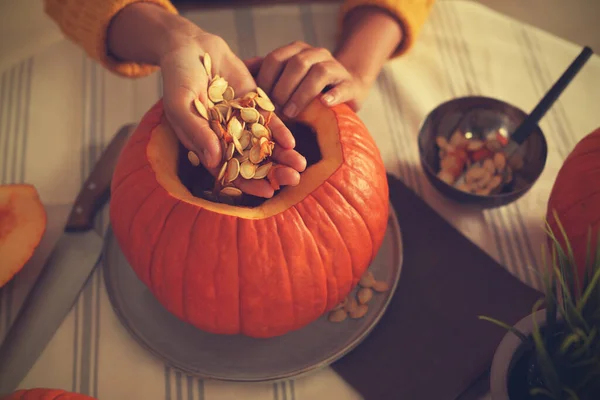 Woman making pumpkin jack o\'lantern at table, closeup. Halloween celebration