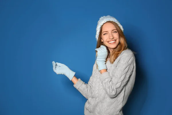 幸せな若い女性身に着けている暖かいセーター ニット帽とミトン上の青の背景 — ストック写真