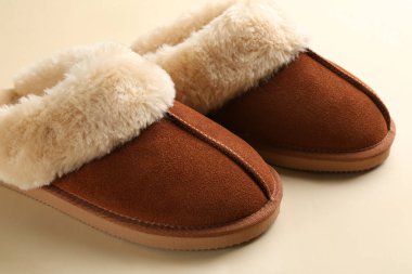 Bej arka planda bir çift şık yumuşak terlik, yakın plan.