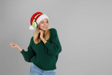 Gri arka planda kulaklıkları olan mutlu kadın, mesaj için yer var. Noel müziği