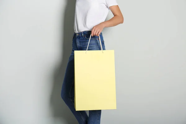 薄いグレーの背景に紙の買い物袋を持つ女性 クローズアップ — ストック写真