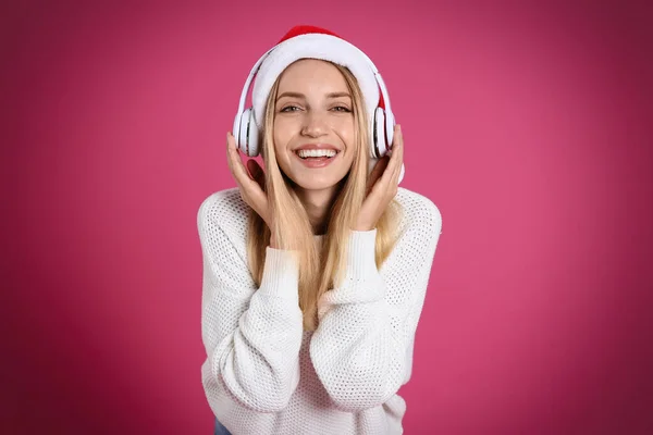 ピンクの背景にヘッドフォンを持つ幸せな女性 クリスマス音楽 — ストック写真